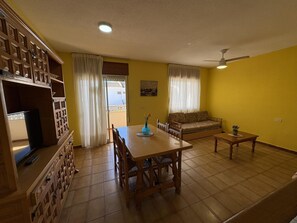 A living room with a dining table, sofa, and a ceiling fan.