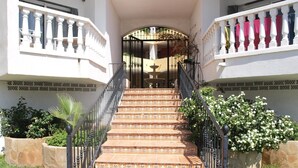 A set of outdoor stairs leading to a building entrance, surrounded by stone planters and greenery. - Beachfront Apartment in Alcoceber with Pool, Jacuzzi, and Garden (Alcocéber)