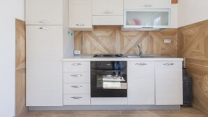 Een praktische keuken met een inbouwoven, een magnetron en een klein spoelbakje.