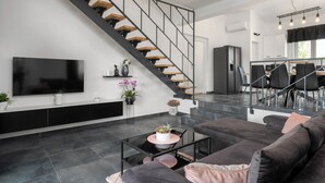 Una sala de estar moderna con una escalera, un televisor de pantalla plana, un comedor y una cocina.