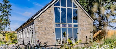 A stone building with large windows and a sloped roof.