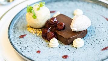 A dessert plate with a chocolate dessert, cherries, and a scoop of ice cream.