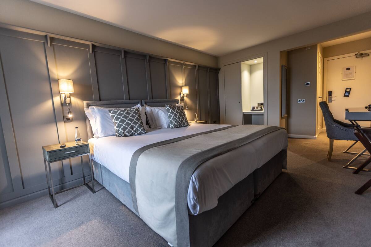 A modern hotel room with a large bed, bedside lamps, a desk, and a chair.