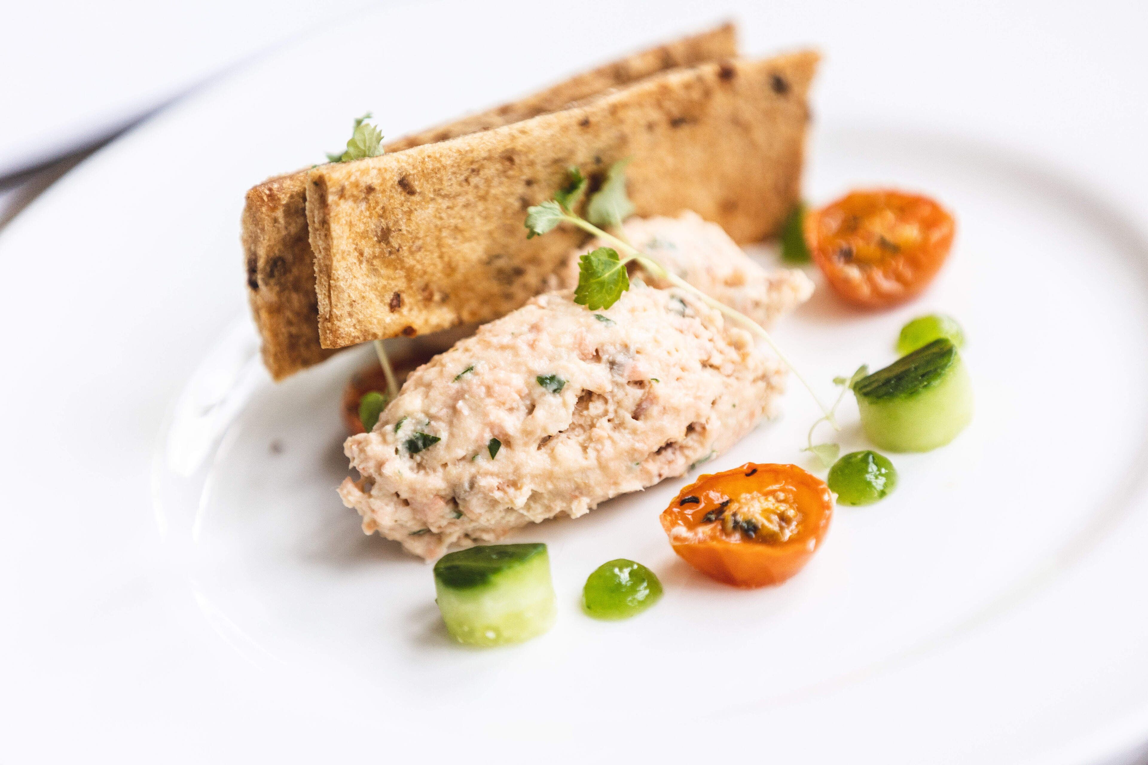 Une assiette avec un sandwich, une tartinade et quelques légumes.