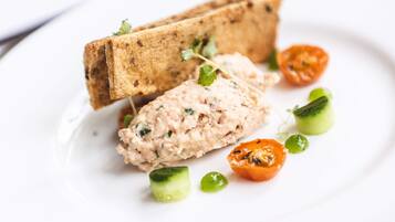 Une assiette avec un sandwich, une tartinade et quelques légumes.