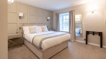 A bedroom with a large bed, bedside tables, a mirror, and a window with curtains.