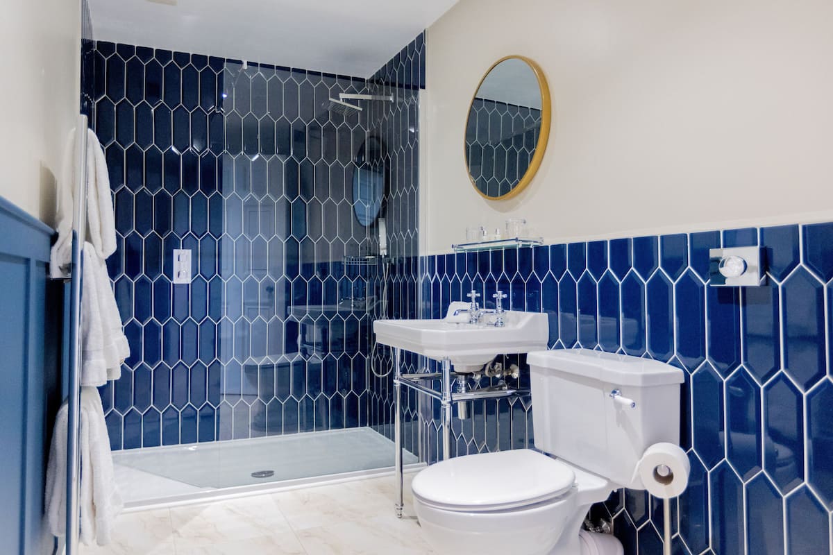 A bathroom with a glass-enclosed shower, a white toilet, and a sink with a mirror above it.