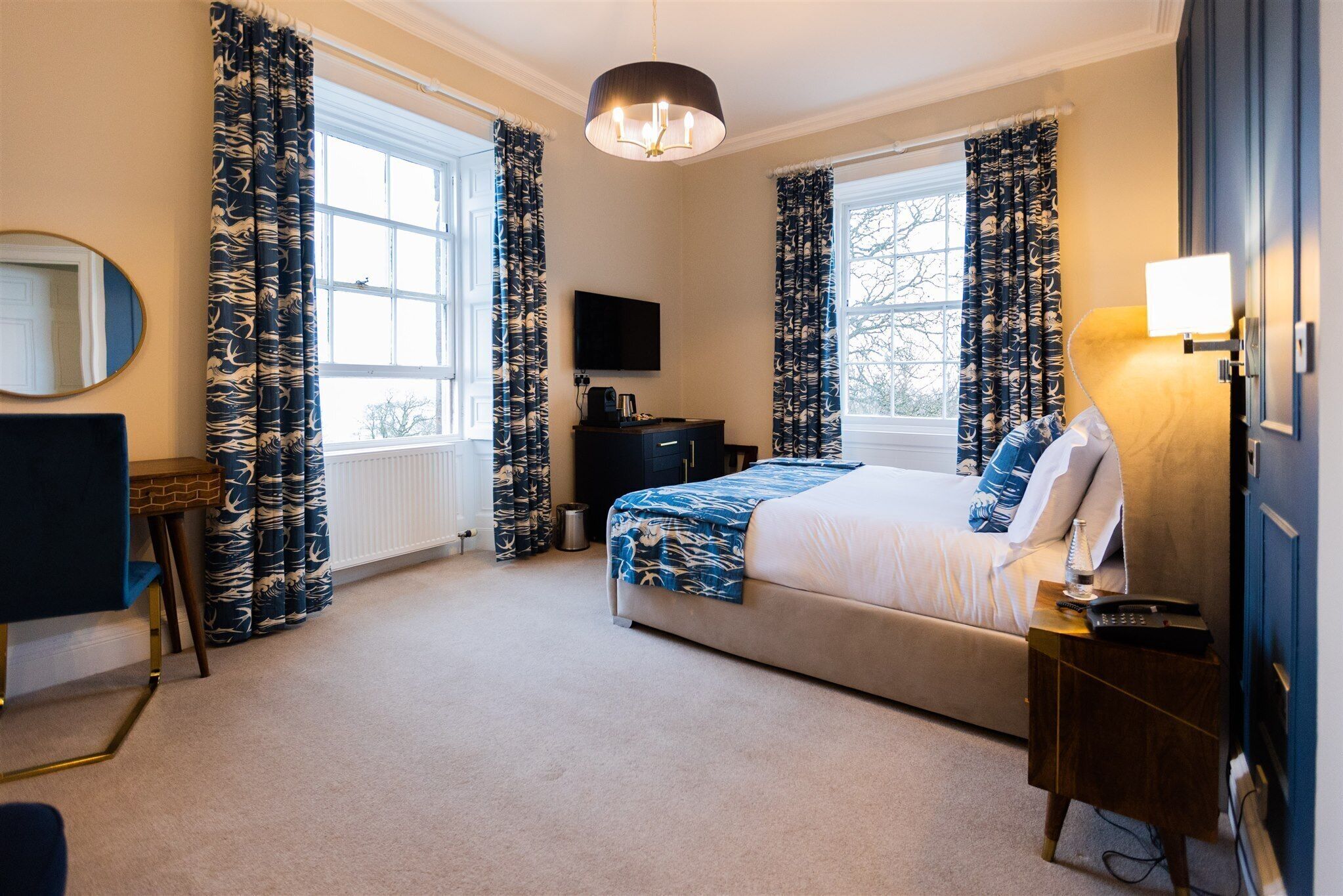 A bedroom with a bed, a TV, a desk, and a lamp.