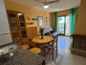 A kitchen with a dining table and chairs, a cabinet with glass doors, and a sofa in the living area. - Apartment in Peniscola with pool, tennis court, and playground (Peñíscola)
