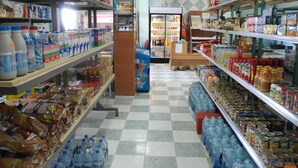 Un pasillo de un supermercado con estantes repletos de diversos productos, como agua embotellada, pan y conservas.