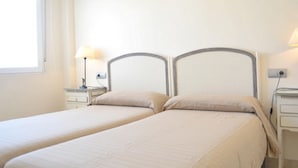 Un lit double avec une tête de lit, une table de chevet avec une lampe et une fenêtre avec des rideaux.