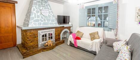 A cozy living room with a stone fireplace, a sofa, and a television.