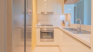 A modern kitchen with white cabinets, a stainless steel stove, and a double sink. - Bellavista- Downtown View II - Burj View (Dubai)
