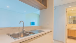 A modern kitchen with a double sink, wooden ceiling beams, and a view into the adjacent bathroom. - Bellavista- Downtown View II - Burj View (Dubai)