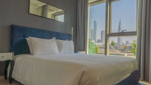 A hotel room with a large bed, a nightstand, a mirror, and a view of a cityscape through large windows. - Bellavista- Downtown View II - Burj View (Dubai)