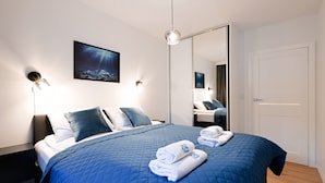 A modern hotel room with a large bed, a mirror, and a painting on the wall. - Aura 40 by Q4 Apartments (Gdansk)