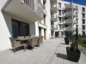 A modern apartment building with outdoor seating and potted plants.
