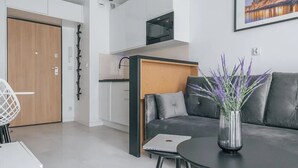 A modern living space with a sofa, a coffee table, a laptop, and a vase with flowers. - Aura 40 by Q4 Apartments (Gdansk)