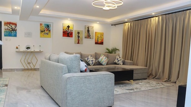 Un salon moderne avec un canapé gris, une table basse noire et un rideau beige.