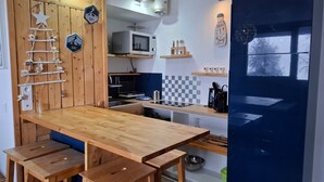 Une cuisine compacte dotée de plans de travail en bois, d’un four à micro-ondes et d’un petit coin repas avec des tabourets.