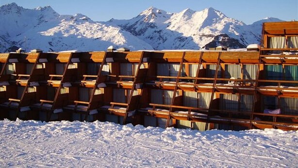 Une rangée de cabanes en bois, avec une montagne enneigée en arrière-plan.