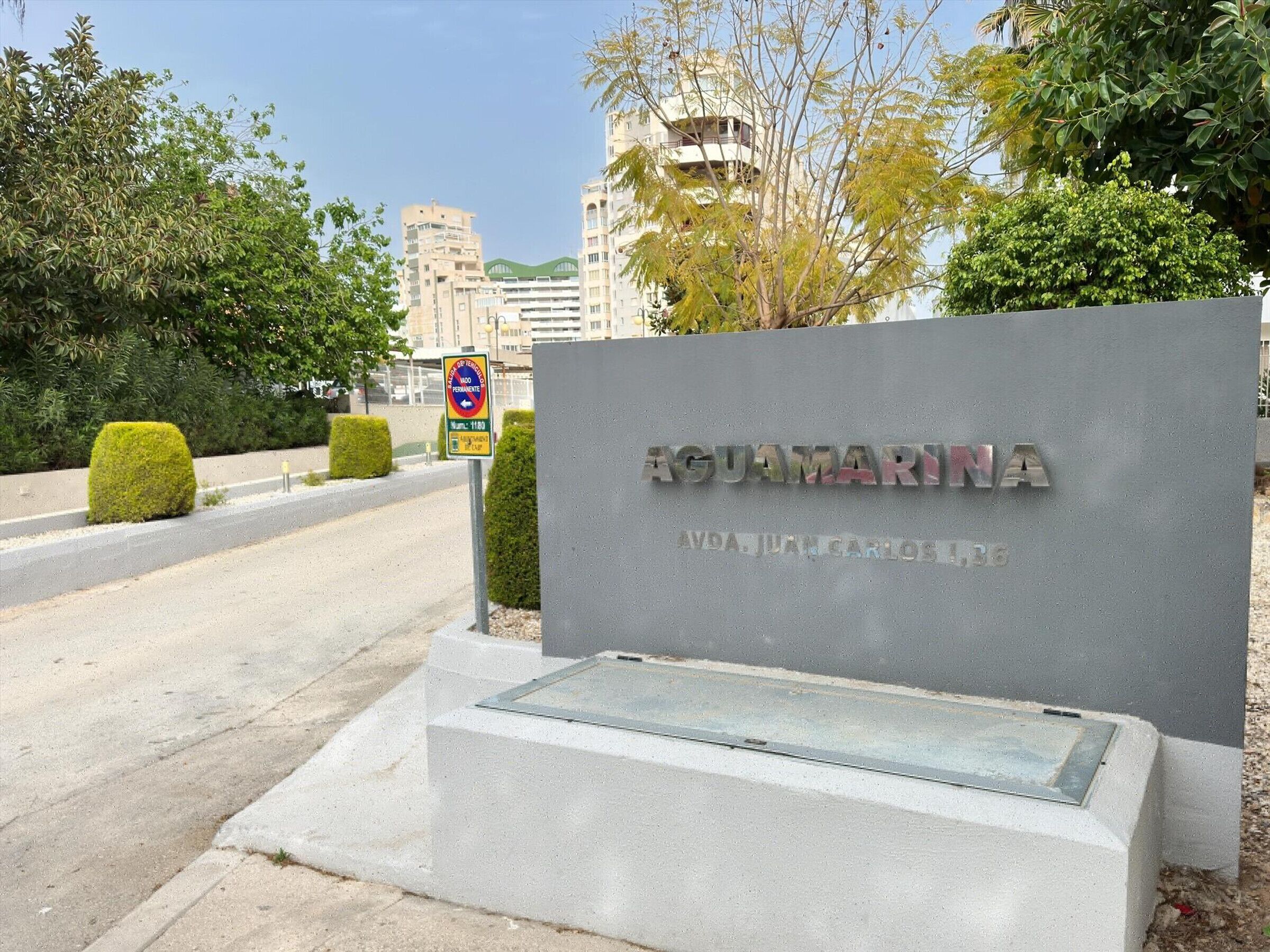 A sign for AQUAMARINA with a clear view of the surrounding area, including a road and buildings in the background.