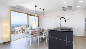 A modern kitchen with a central island, white chairs, and a dining table set for six. - Our Ocean Penthouse, luxury, views y relax ! (Guía de Isora)