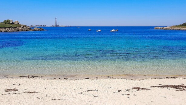 A beach with clear blue water, a lighthouse, and boats. - Awesome home in Plouguerneau with house sea view (Plouguerneau)