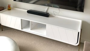 A flat-screen TV mounted on a white entertainment unit with a cable box below.