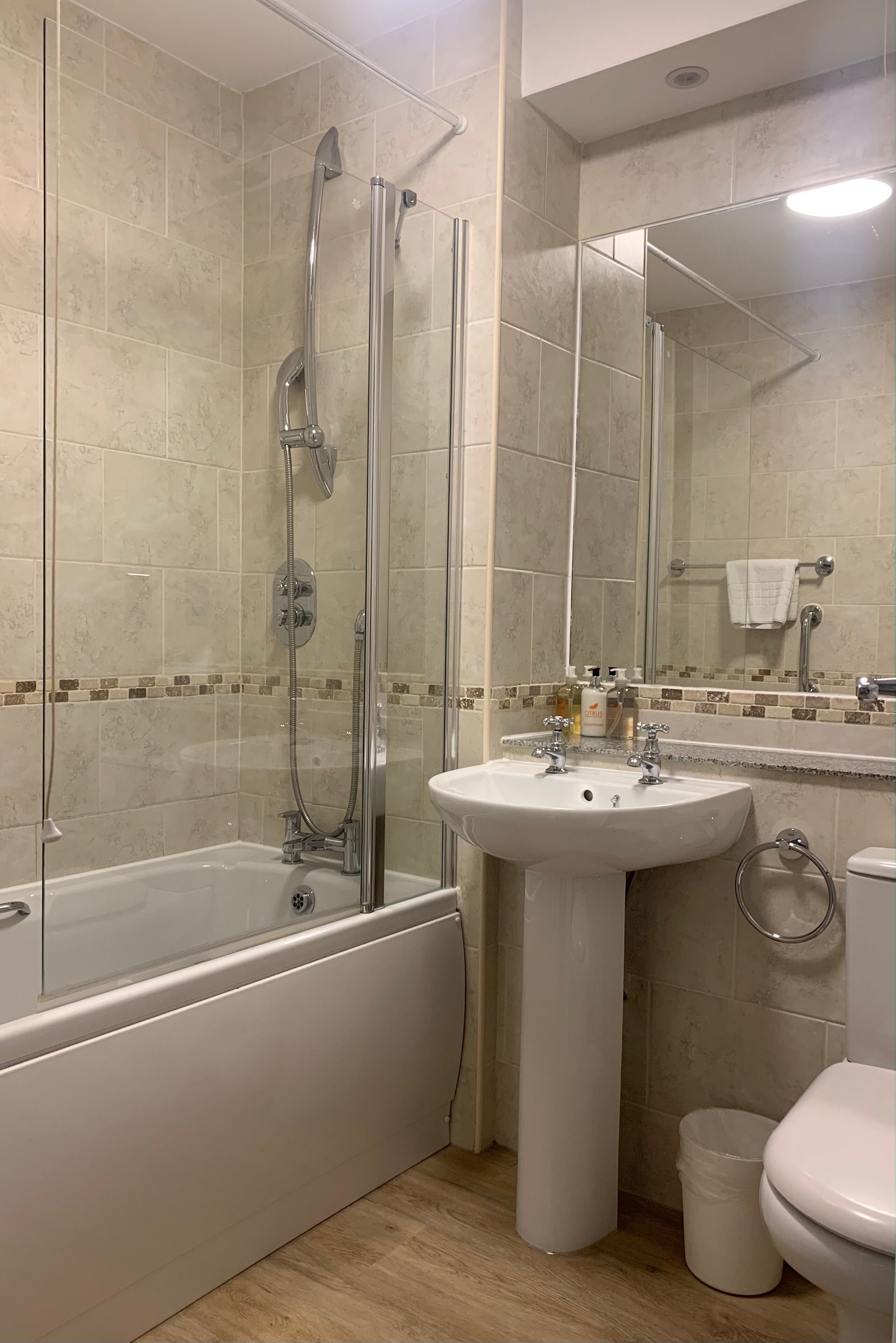 Une salle de bain moderne avec une douche à parois de verre, une baignoire sur pieds, un lavabo sur colonne et des toilettes.