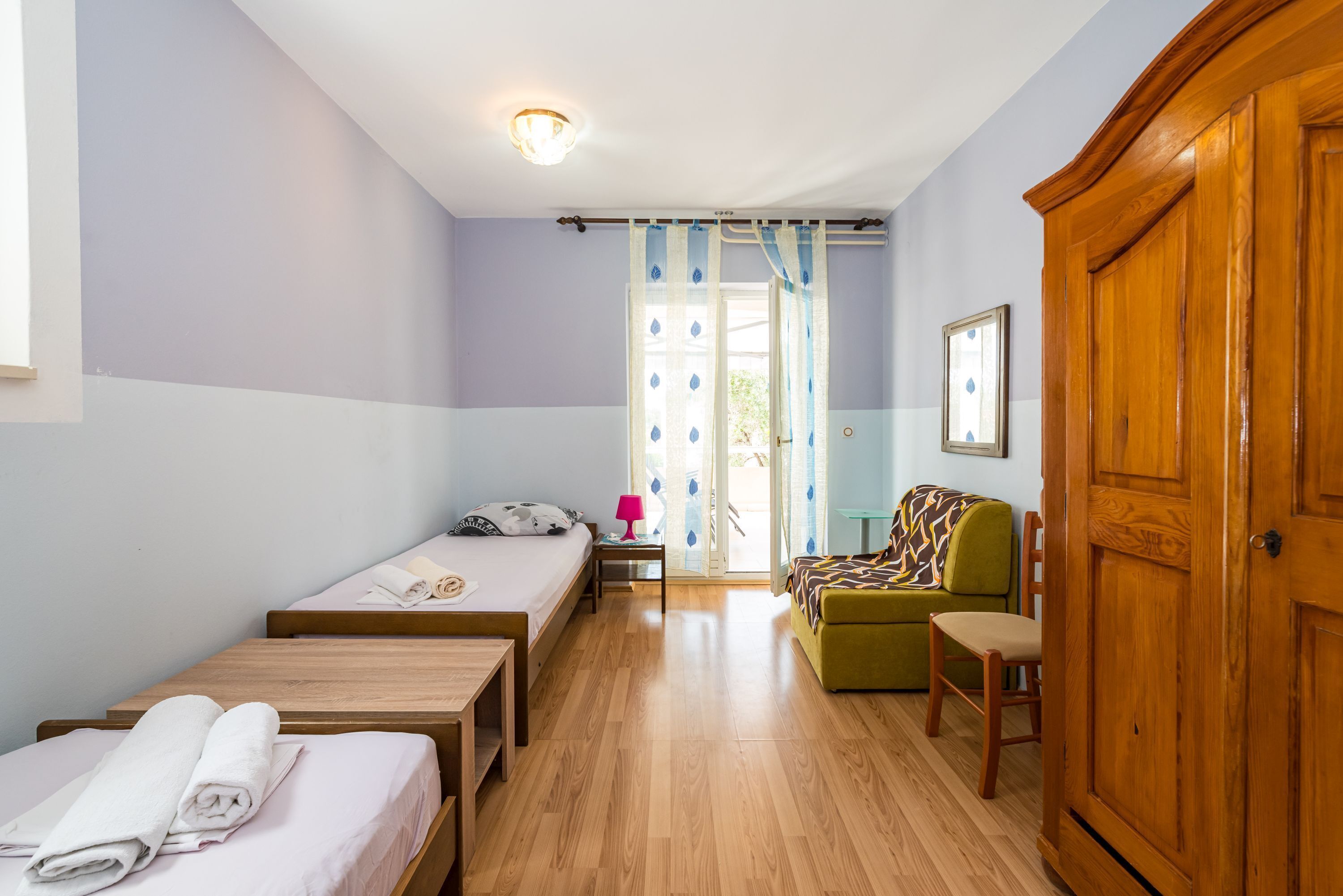 Ein Zimmer mit einem Bett, einem kleinen Tisch, einem Stuhl, einer Couch und einem Schrank.