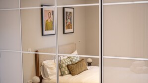Una camera da letto con un letto, cuscini, un comodino e due quadri appesi al muro.