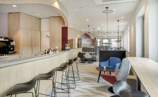 A modern bar area with a long counter, bar stools, and seating.