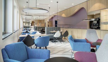 A modern hotel lobby with seating areas, a coffee bar, and a view of the interior.
