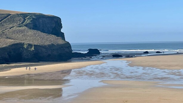 Une plage avec une grande formation rocheuse et un rivage sablonneux.
