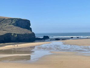 A beach with a large rock formation and a sandy shoreline. - Breathtaking Sea Views, Two minutes walk to Beach - Mawgan Porth, Cornwall (Mawgan Porth)