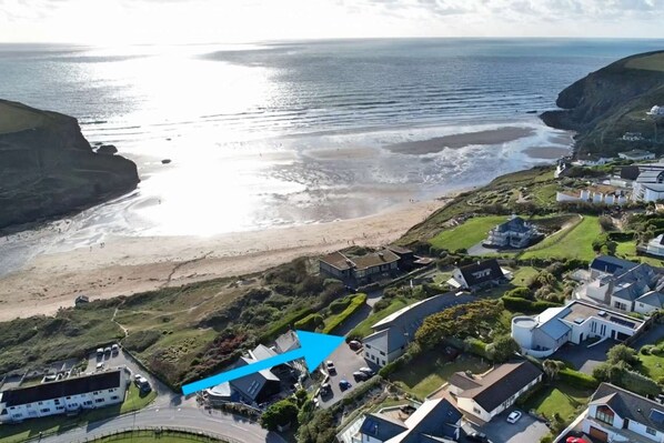 An aerial view of a coastal residential area with houses, a beach, and cliffs. - Breathtaking Sea Views, Two minutes walk to Beach - Mawgan Porth, Cornwall (Mawgan Porth)