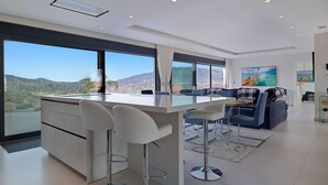 Een moderne keuken met een centraal eiland, barstoelen en een eethoek met uitzicht op de bergen.