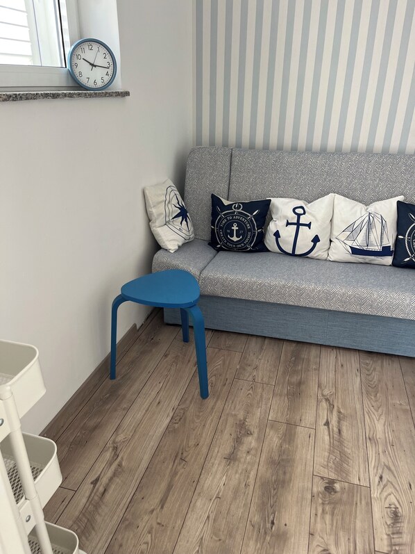 A modern living room with a grey sofa, nautical-themed pillows, a blue table, and a wooden floor. - Salt&sea Summerhouse Mandre, 30m vom Strand, Garten,whirlpool,meerblick (Mandre)