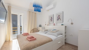 Een slaapkamer met een bed, nachtkastjes, een kledingkast, een plafondventilator en een raam met gordijnen.