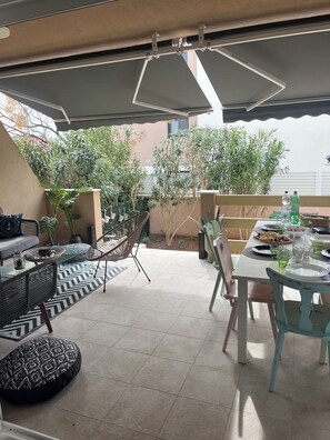 A patio with outdoor furniture, a dining table set, and potted plants.