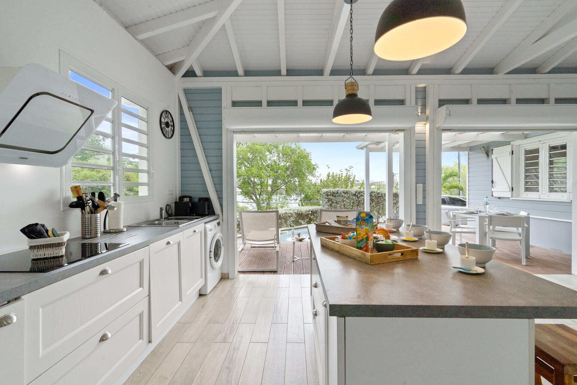 A spacious kitchen with a large island, a dining area with outdoor seating, and a view of the outdoors.