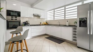 Una cocina moderna con armarios blancos, un refrigerador de acero inoxidable, un horno Bosch y una estufa a gas.