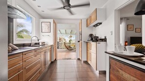 A modern kitchen with wooden cabinets, a built-in stove, and a view to a balcony with a hanging chair.