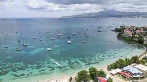 A coastal town with a marina filled with sailboats, clear turquoise waters, and a beach area with buildings and greenery. - Villa Kavich - Two Bedroom Villa, Sleeps 4 (Les Trois-Îlets)