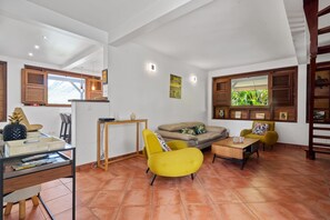 Una sala de estar con sofá, sillas, una mesa de centro y un comedor con mesa y sillas.