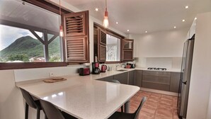 Una cocina moderna con una isla grande, electrodomésticos de acero inoxidable y contraventanas de madera.