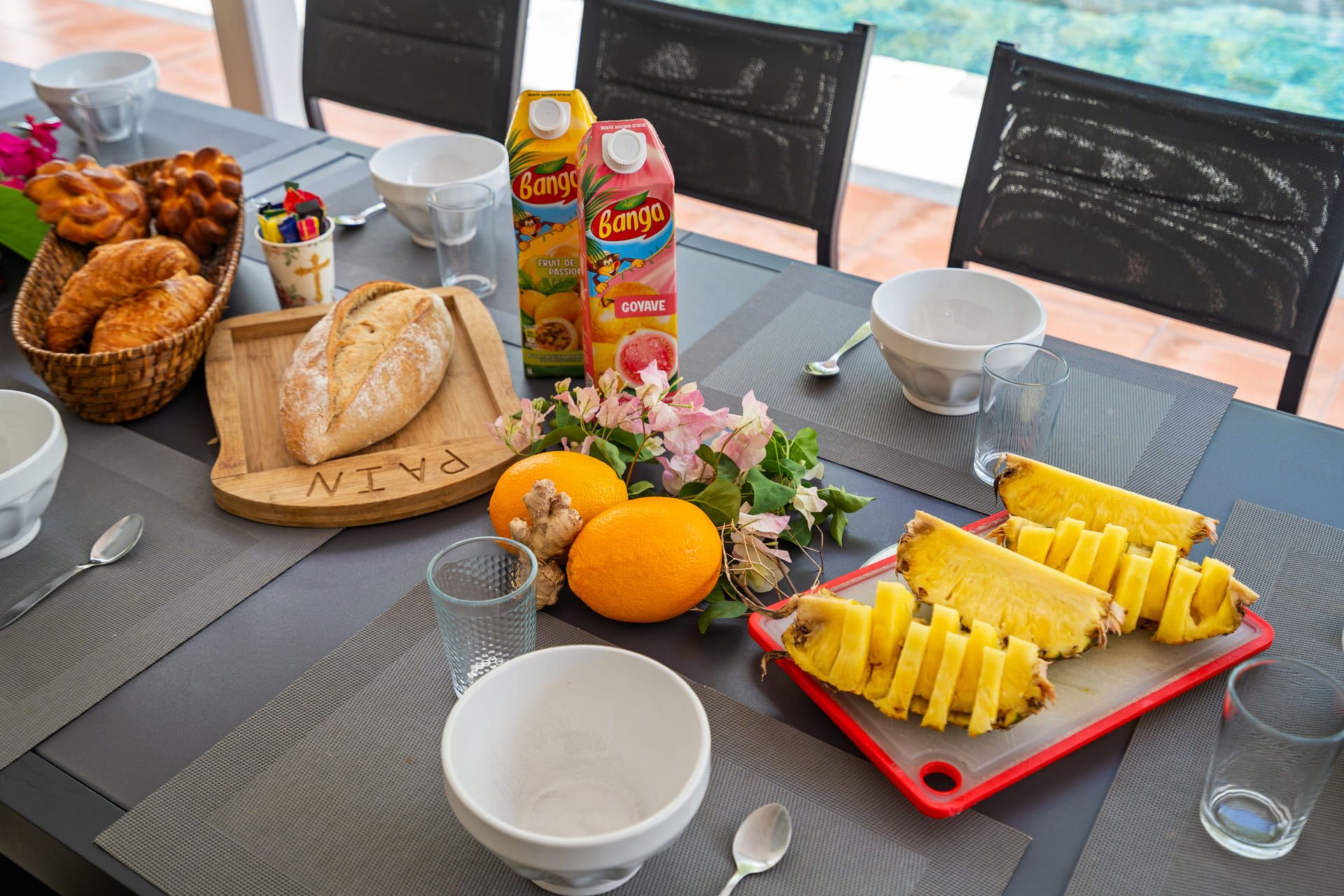 Una mesa de desayuno con pan, fruta y un cartón de jugo.