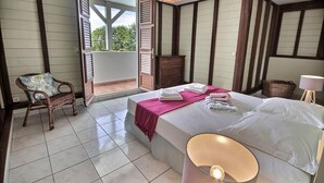 Un dormitorio con cama, una silla, un aparador y un balcón.