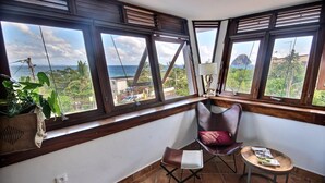 A corner room with a view of the ocean, a chair, a small table, and a lamp. - Villa Kaléna - Four Bedroom Villa, Sleeps 9 (Le Diamant)